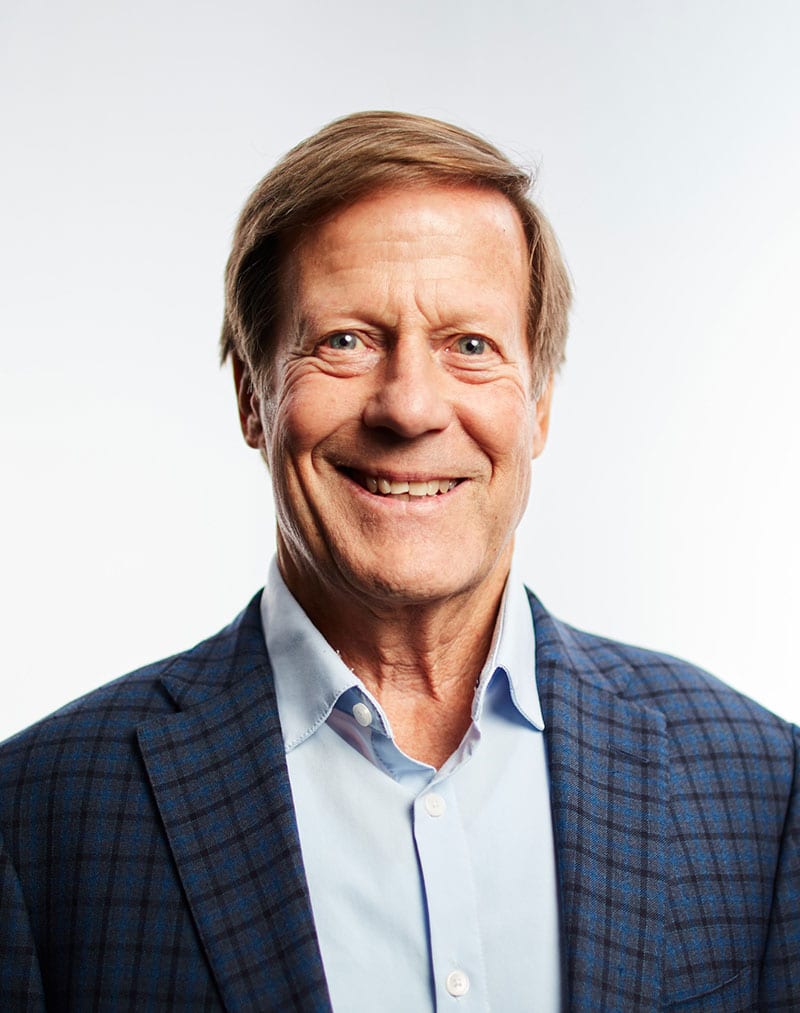 a man wearing a suit and tie smiling at the camera