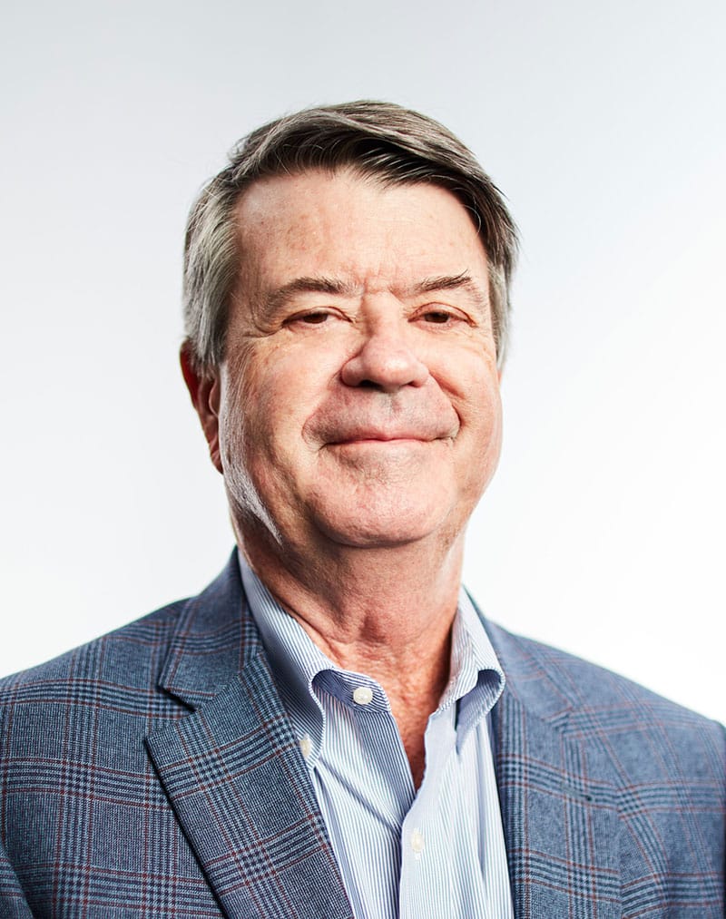 a man wearing a suit and tie smiling at the camera