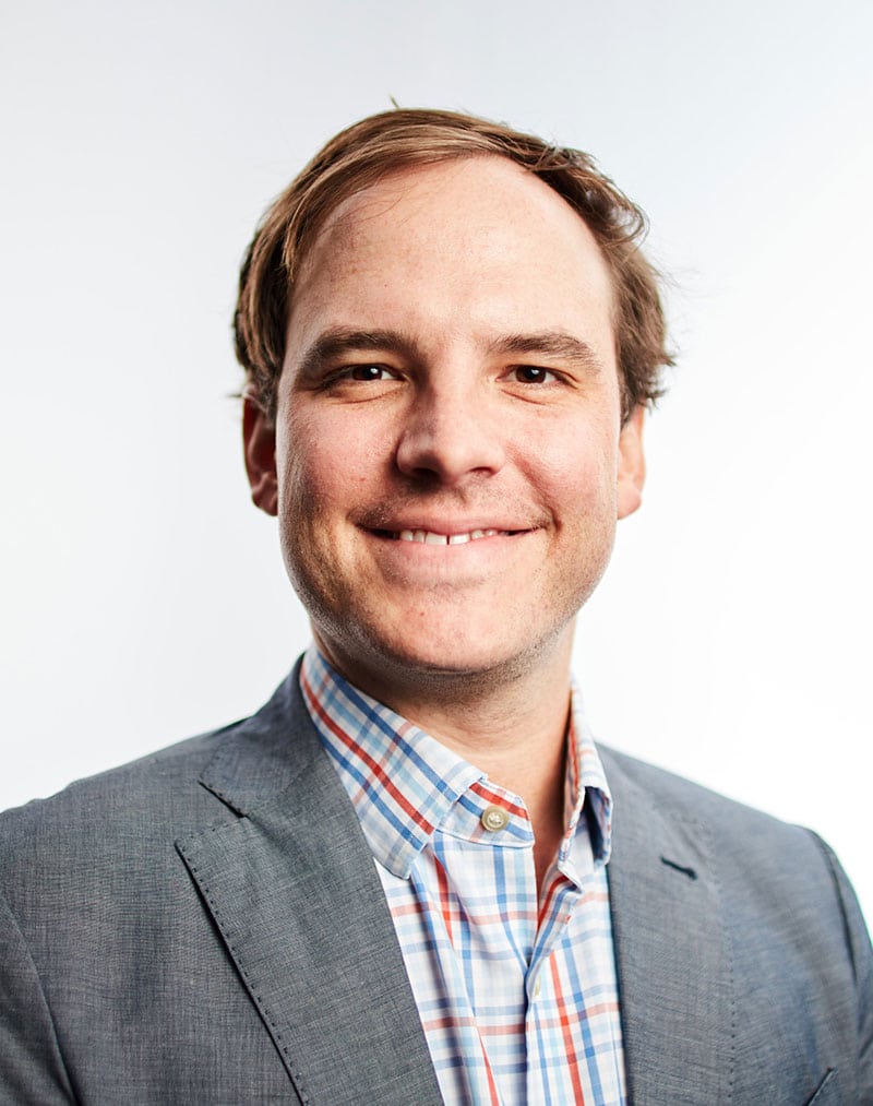 a man wearing a suit and tie smiling at the camera