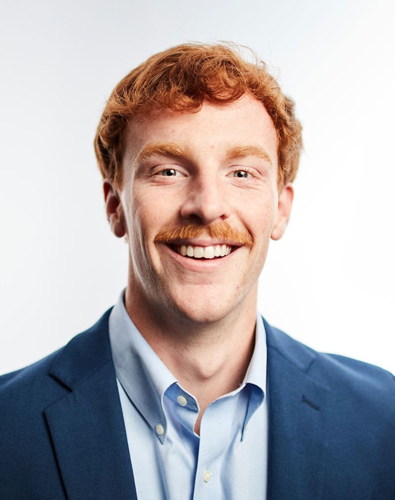 a man wearing a suit and tie smiling at the camera